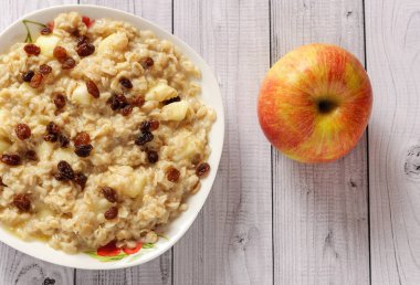 Elma ve üzüm eski ağaç arka planı yulaf ezmesi. Bir elma ve kuru üzüm ile müsli