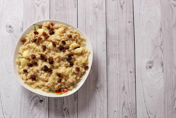 Elma ve üzüm eski ağaç arka planı yulaf ezmesi. Bir elma ve kuru üzüm ile müsli