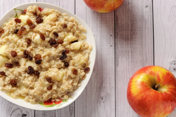 Elma ve üzüm eski ağaç arka planı yulaf ezmesi. Bir elma ve kuru üzüm ile müsli