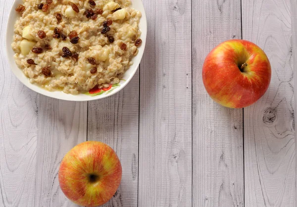 Elma ve üzüm eski ağaç arka planı yulaf ezmesi. Bir elma ve kuru üzüm ile müsli