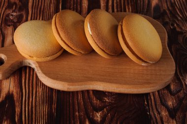 Muz üzerinde eski bir ahşap masa doldurma ile lezzetli bisküviler. Şekerli tatlı