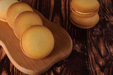 Muz üzerinde eski bir ahşap masa doldurma ile lezzetli bisküviler. Şekerli tatlı