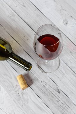 Bir cam ve ahşap masa lambası bir şişe kırmızı şarap