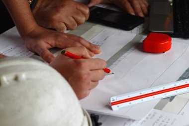 İnşaat işçileri inşaat planlarına danışıyor.