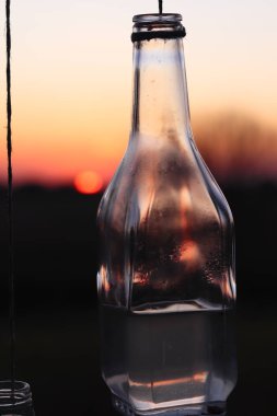 Gün batımı arka planında asılı duran yakın çekim şişesi