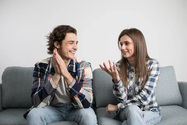 Молода пара говорить і сміється на дивані у вітальні — стокове фото
