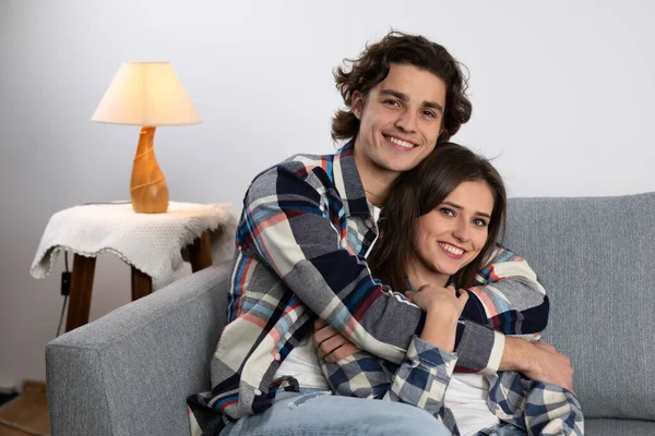 Усміхнений молодий чоловік обіймає дівчину на дивані — стокове фото