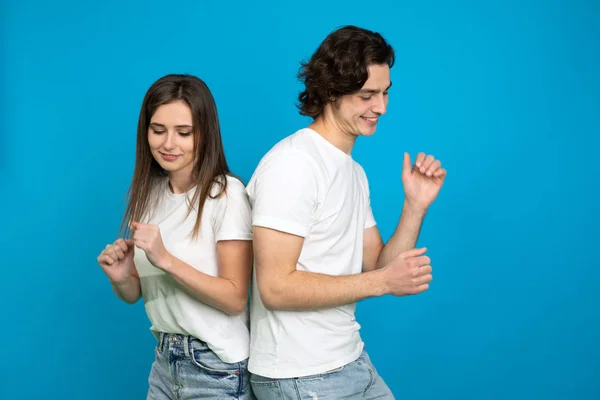 Щаслива пара в білих футболках танцює ізольовано на синьому фоні — стокове фото