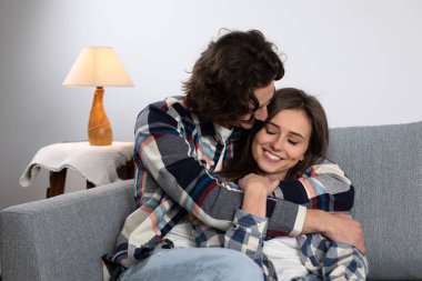 Kanepede birbirine sarılan kareli gömlekli mutlu çift.