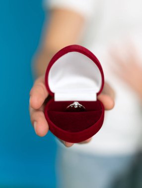 Mavi arka planda nişan yüzüğü tutan adam görüntüsü