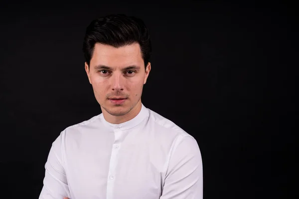 Serious guy looking at the camera. Dressed in a white shirt, black background — 스톡 사진