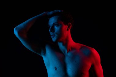 Stüdyoda kırmızı ve mavi renkli bir adam var. Kameraya bak ve gülümse.