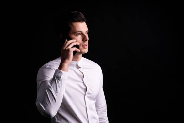 Ellerinde telefon olan yalnız genç bir adam. Buraya bak ve düşün.