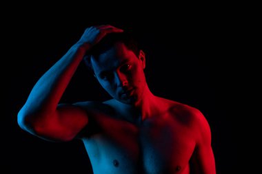 Stüdyoda kırmızı ve mavi renkli bir adam var. Kameraya bak ve gülümse.