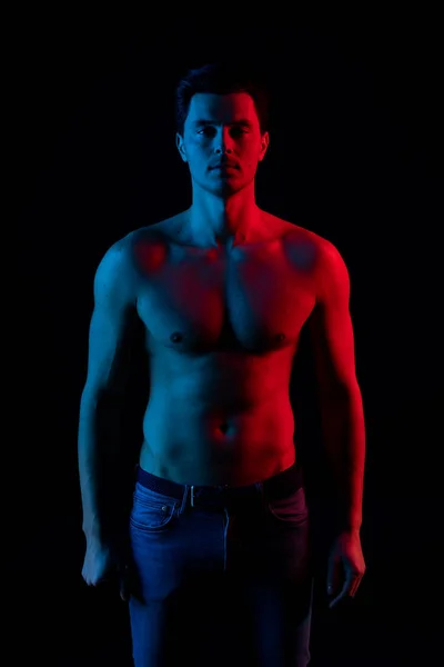 Hombre en estudio con colores rojo y azul. Mira la cámara y sonríe — Foto de Stock