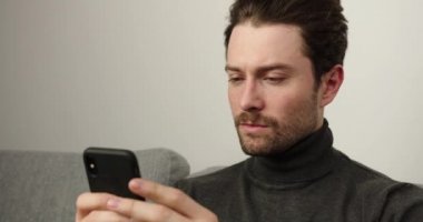 Genç erkekler evdeki akıllı telefonları kullanarak kanepede dinleniyorlar. Genç adam mesaj yazıyor, davaların listesi. Odaklanmış kişi. İçeride.