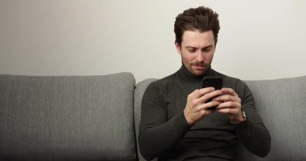 Homem bonito usando smartphone em casa. oncentrated person.Indoor — Vídeo de Stock