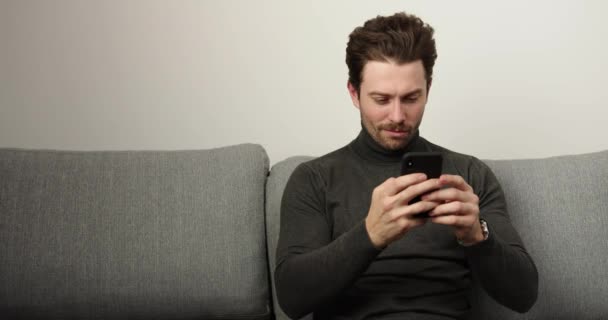 Un bel homme utilisant un smartphone à la maison. personnecentrée. Intérieur — Video