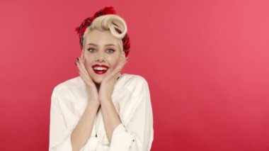 Şaşırmış sarışın kız, kameraya gülümseyerek bakıyor.