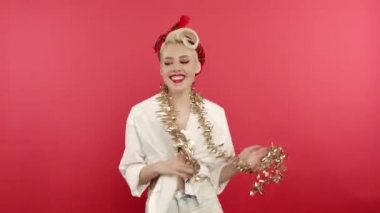 Gülümseyen kız yeni yıl süsleriyle dans ediyor ve hava öpücüğü gönderiyor.