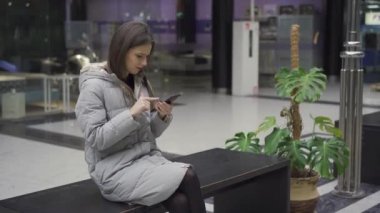 Bankta oturup erkek arkadaşınla konuşurken akıllı telefondan yazı yazan bir kız.