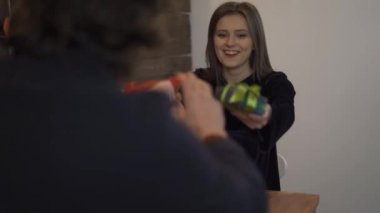 Gülümseyen kız arkadaşla hediyeleri değiş tokuş eden adamın görüntüsü.