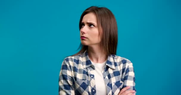 Chica pensativa mirando a su alrededor y mostrando idea signo con sonrisa aislada sobre fondo azul — Vídeo de stock