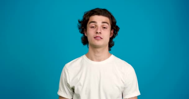 Vista frontal del joven guapo sonriendo aislado sobre fondo azul — Vídeos de Stock