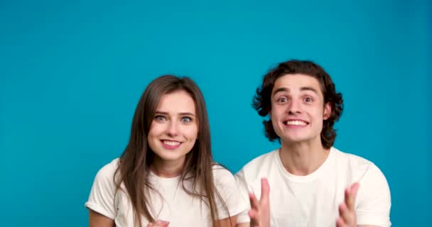 Excited couple looking at camera, smiling, holding hands and embracing isolated on blue background — Stock Video