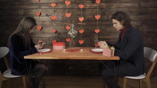 Paar met behulp van smartphones tijdens romantische date in cafe — Stockvideo