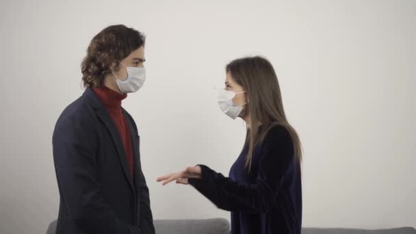 Giovane uomo e donna in maschere protettive che parlano e si guardano — Video Stock