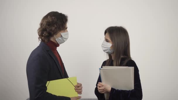 Young man and woman in medical masks with folders talking and looking at each other — Stock Video