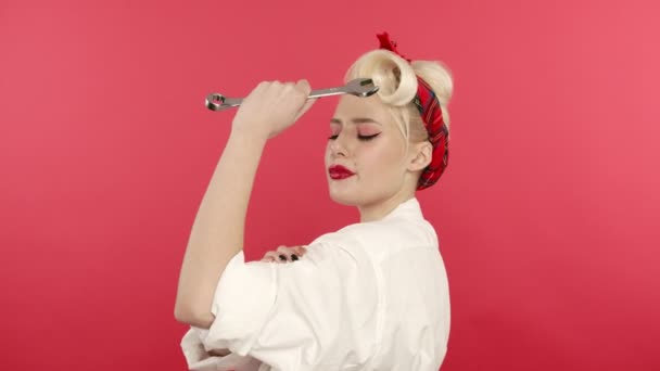 Подцепить блондинку, держащую гаечный ключ и трогающие бицепсы на розовом фоне — стоковое видео
