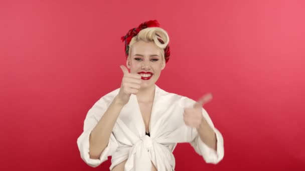 Excited blonde pin up girl showing thumbs up on pink background — Stock Video