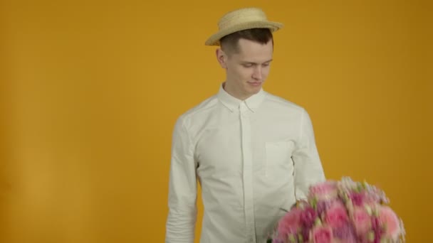 Knappe jongeman die glimlachend naar bloemen kijkt — Stockvideo