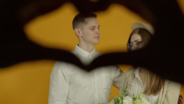 Lyckligt par kysser och skrattar på gul bakgrund — Stockvideo
