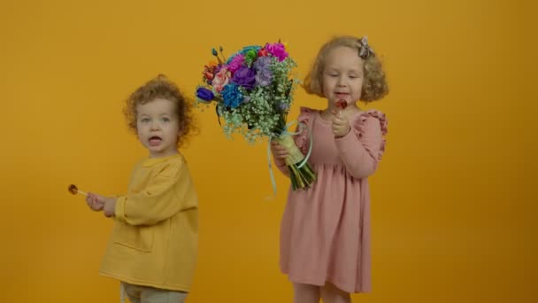 Gelukkige kinderen met bloemen omarmen en eten lolly 's — Stockvideo