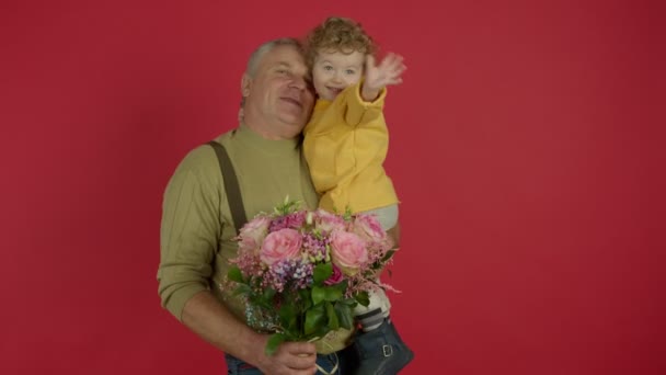 Sorrindo homem sênior segurando flores e beijando neto — Vídeo de Stock