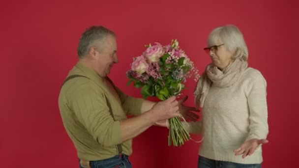 Çiçekleri sunan ve karısını öpen kıdemli adam. — Stok video