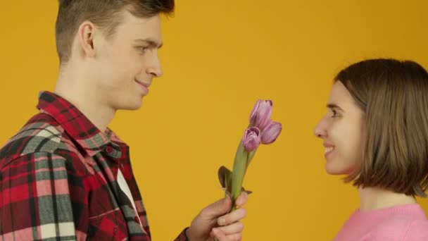फुलं धारण आणि चुंबन गर्लफ्रेंड हसत मनुष्य साइड दृश्य — स्टॉक व्हिडिओ