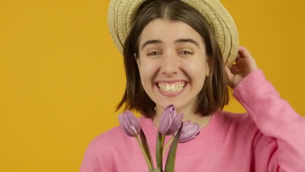 Excited girl in hat showing tulips and winking with smile — Stock Video