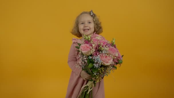 Criança encaracolado feliz segurando buquê e tocando flores — Vídeo de Stock