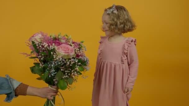 Alegre niño rizado mirando flores y saltando sobre fondo amarillo — Vídeos de Stock