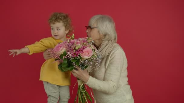 Abuela sosteniendo flores y madre abrazando al niño — Vídeo de stock