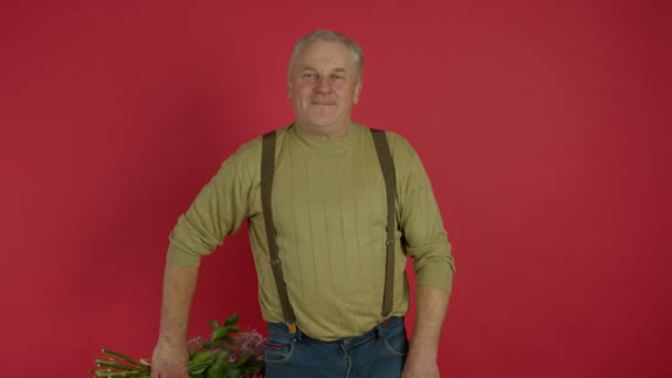 Веселый пожилой мужчина показывает цветочный букет в камеру — стоковое видео