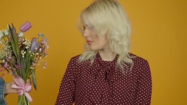 Оскорбленная блондинка отказывается от букета тюльпана и стоит со скрещенными руками — стоковое видео