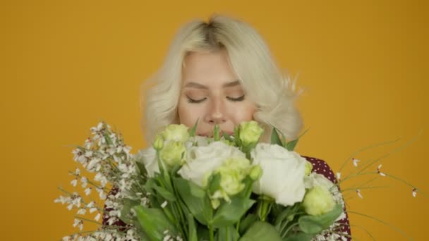Вид спереду щаслива білявка дівчина нюхає квіти із закритими очима — стокове відео