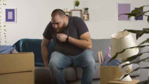 Hombre barbudo con sobrepeso sentado en el sofá, comiendo palomitas de maíz y viendo la televisión — Vídeo de stock