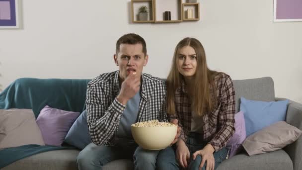 Focado casal assistindo tv e jogando pipocas para câmera com expressão rosto chateado — Vídeo de Stock