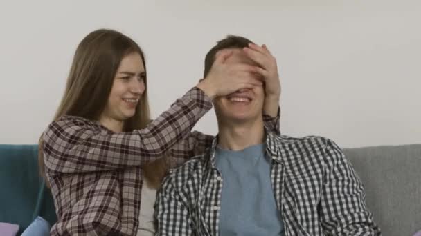 Rindo menina cobrindo os olhos para namorado e assistindo tv — Vídeo de Stock